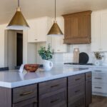 The image is a photo of an indoor kitchen with white cabinets and brown countertops.