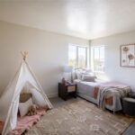 The room is white with a teepee and stuffed animal.
